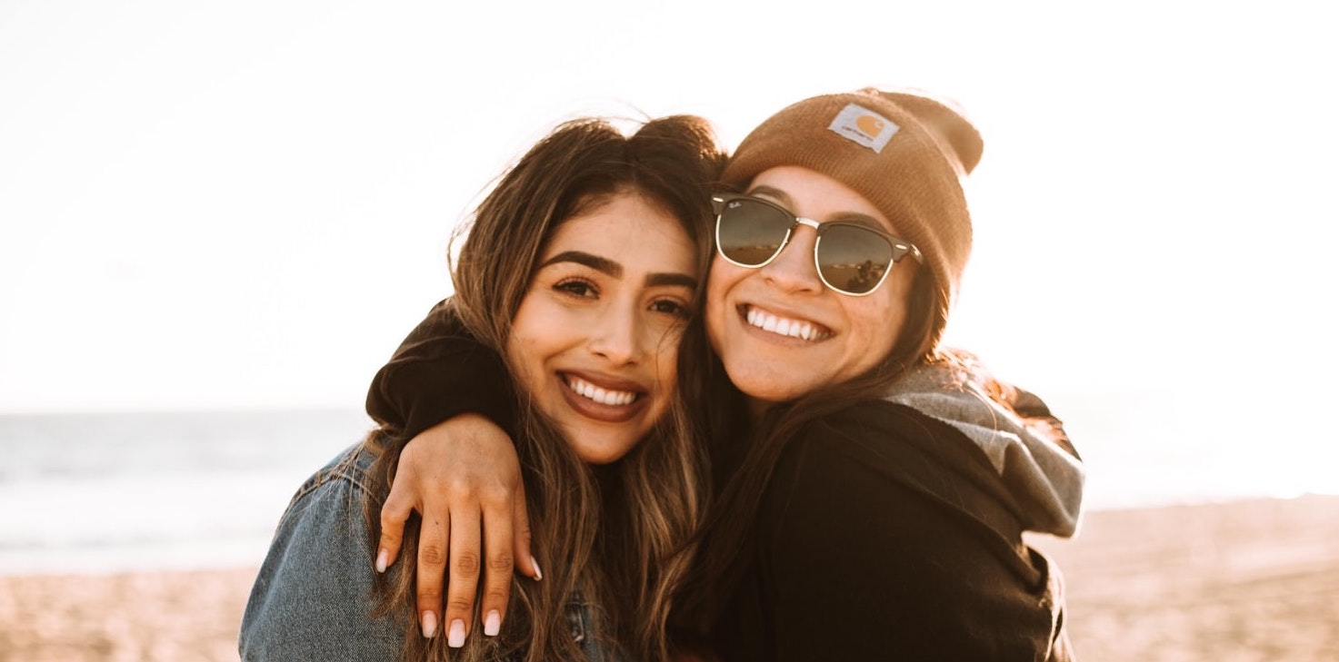 Photo of two women embracing an posing for the camera.