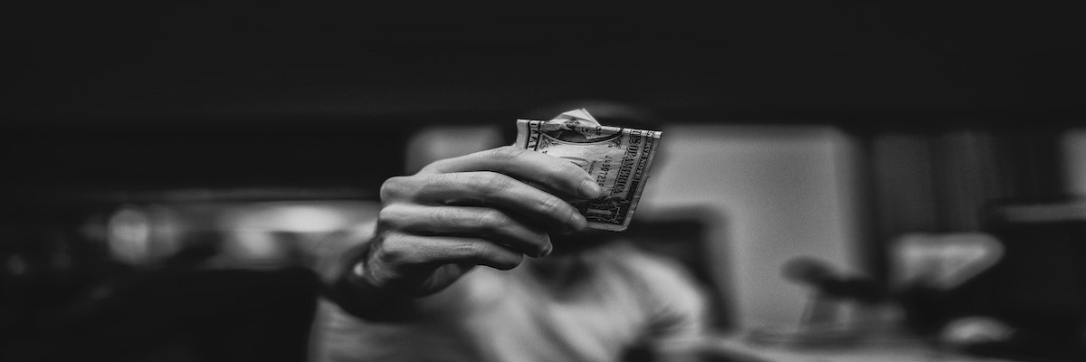 Photo of a hand holding dollar bills.