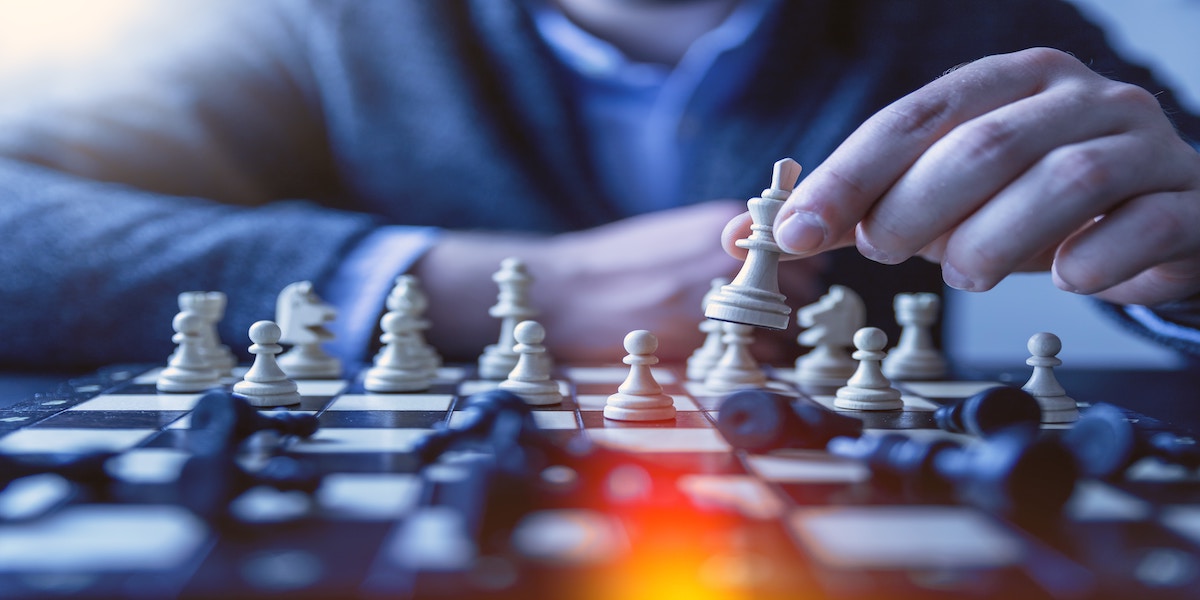 Photo of a person playing chess about to make a move with the white queen.