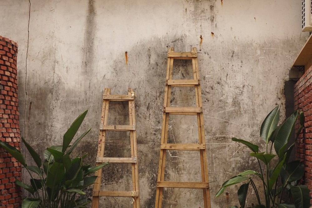 Two small wooden ladders leaning against a wall.