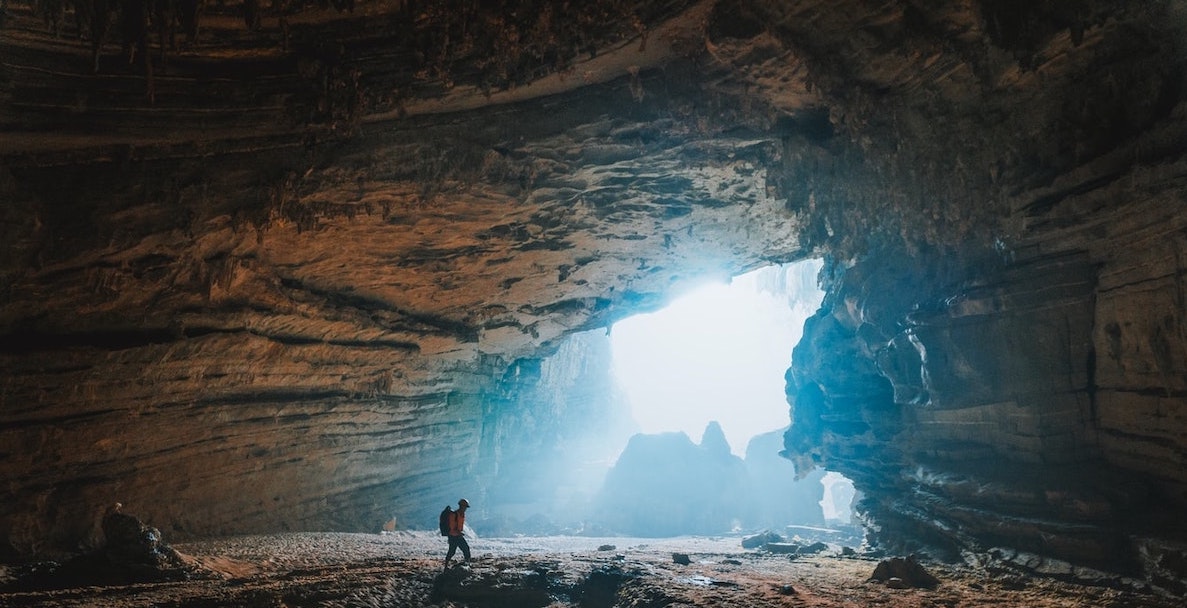 Photo of a man wearing a backpack hiking inside a cave.
